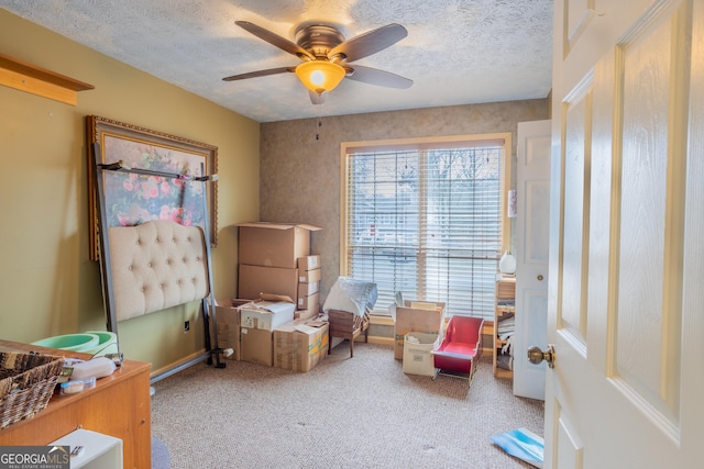 sitting room with a ceiling fan, light carpet, and a textured ceiling