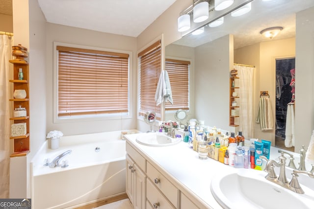 bathroom with double vanity, a textured ceiling, a bath, and a sink