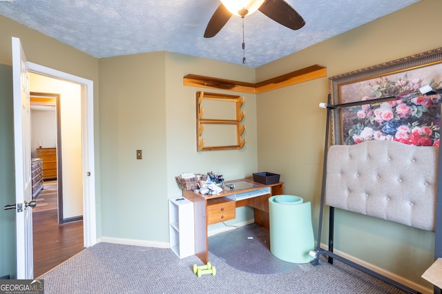 carpeted home office with baseboards, a ceiling fan, and a textured ceiling