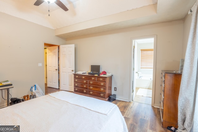 bedroom with baseboards, vaulted ceiling, ensuite bath, wood finished floors, and a ceiling fan