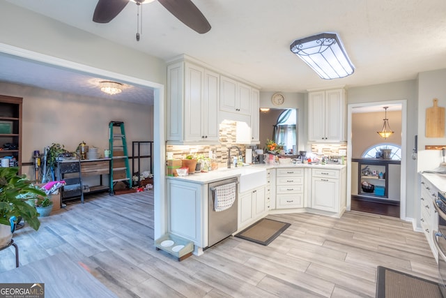 kitchen with light countertops, tasteful backsplash, a sink, and dishwasher