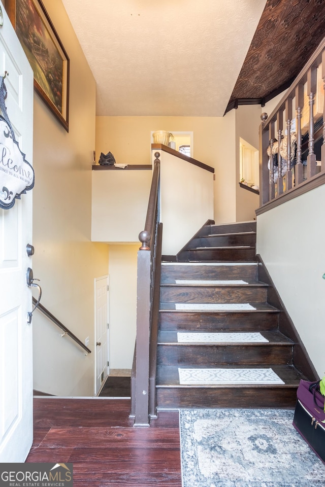 stairs with a textured ceiling and wood finished floors