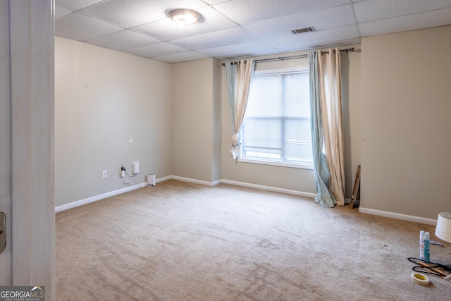 empty room featuring baseboards, visible vents, light colored carpet, and a drop ceiling