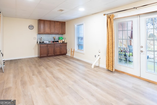 bar with a paneled ceiling, baseboards, backsplash, and light wood finished floors