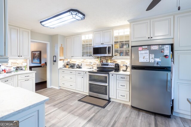 kitchen with light countertops, glass insert cabinets, stainless steel appliances, and white cabinets