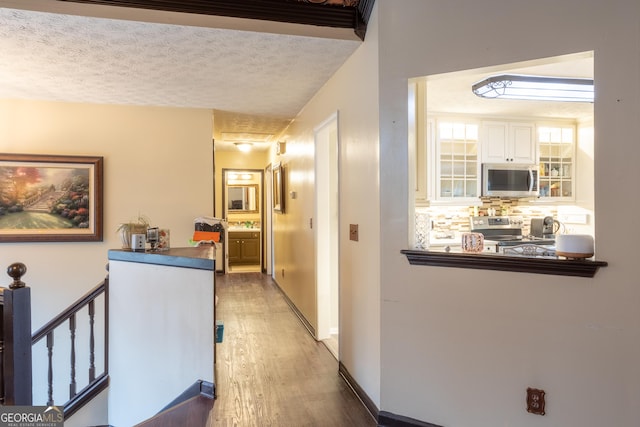 hallway with an upstairs landing, dark wood-style floors, a textured ceiling, and baseboards