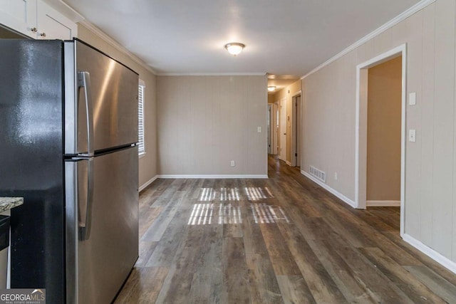 kitchen featuring dark hardwood / wood-style floors, white cabinetry, ornamental molding, and stainless steel refrigerator