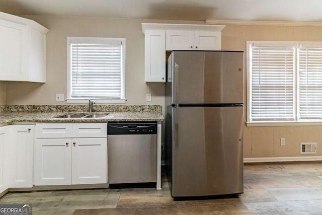 kitchen with sink, crown molding, stainless steel appliances, light stone counters, and white cabinets