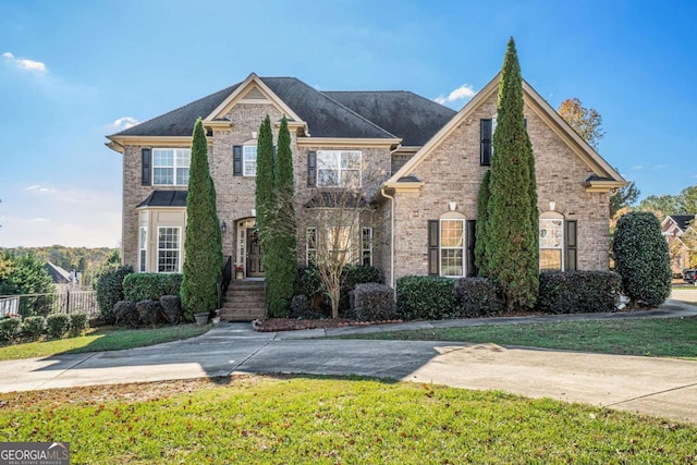 traditional-style home featuring brick siding, a front lawn, and fence