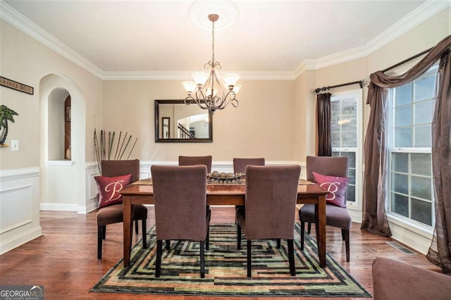 dining room featuring visible vents, arched walkways, dark wood-style floors, a wainscoted wall, and a chandelier