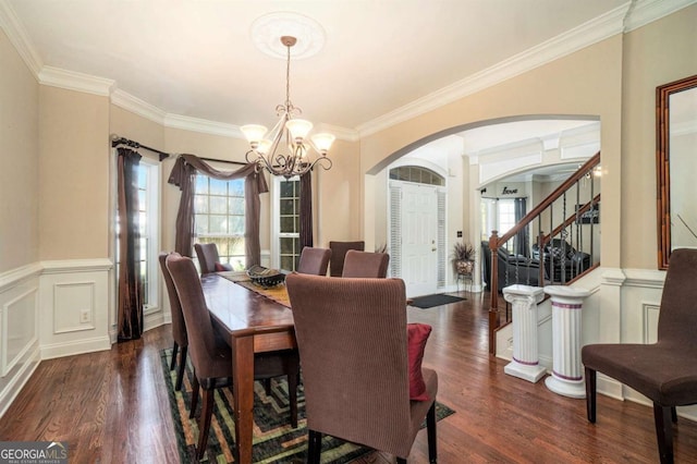 dining space featuring a chandelier, wainscoting, stairway, and wood finished floors