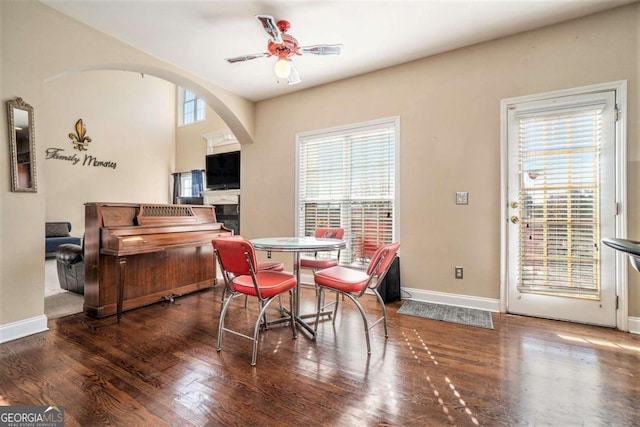 sitting room with arched walkways, wood finished floors, a ceiling fan, and baseboards