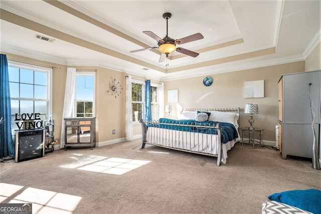 carpeted bedroom featuring ornamental molding, a tray ceiling, visible vents, and baseboards