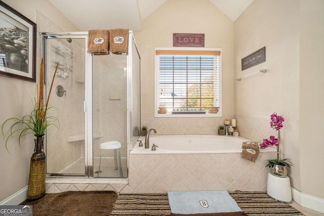 full bathroom featuring lofted ceiling, a garden tub, a shower stall, and baseboards