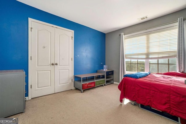 carpeted bedroom with visible vents and a closet