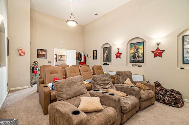 cinema room featuring a towering ceiling, light carpet, visible vents, and baseboards