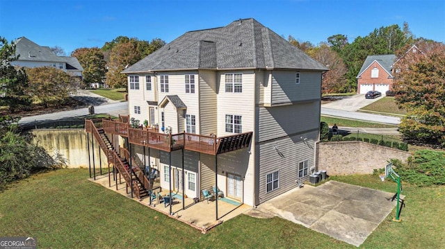 back of property featuring a shingled roof, stairway, a lawn, a wooden deck, and a patio area