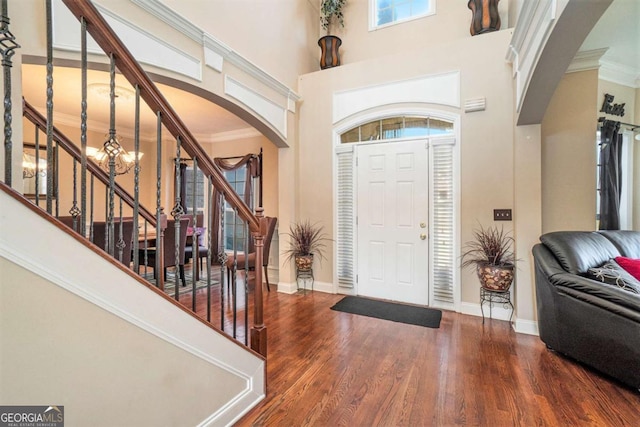 foyer entrance with ornamental molding, stairway, wood finished floors, and baseboards