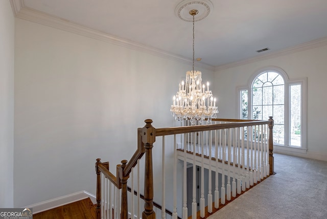 staircase with an inviting chandelier, ornamental molding, and carpet