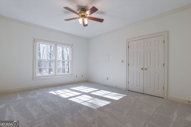 carpeted spare room featuring crown molding and ceiling fan