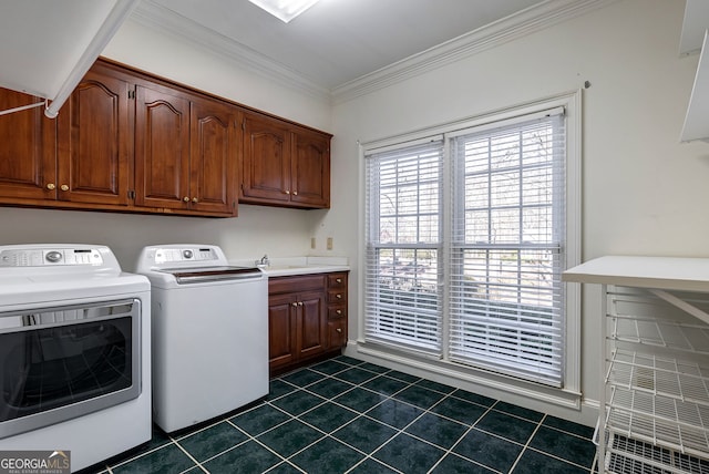 laundry room with crown molding, cabinets, washing machine and dryer, and dark tile patterned floors