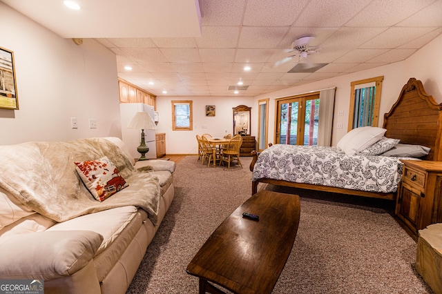 bedroom featuring ceiling fan, multiple windows, carpet flooring, a drop ceiling, and access to outside