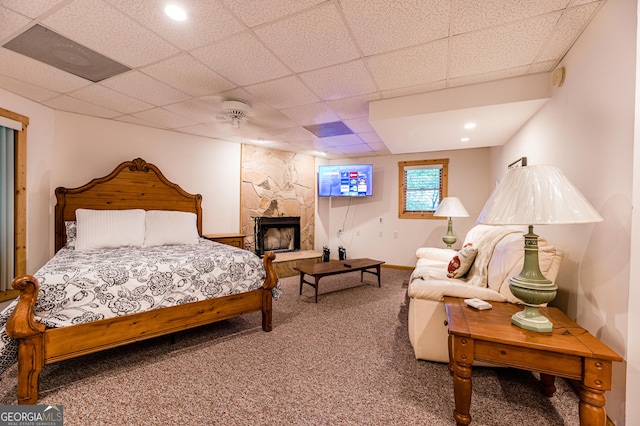 bedroom with ceiling fan, carpet floors, a paneled ceiling, and a fireplace