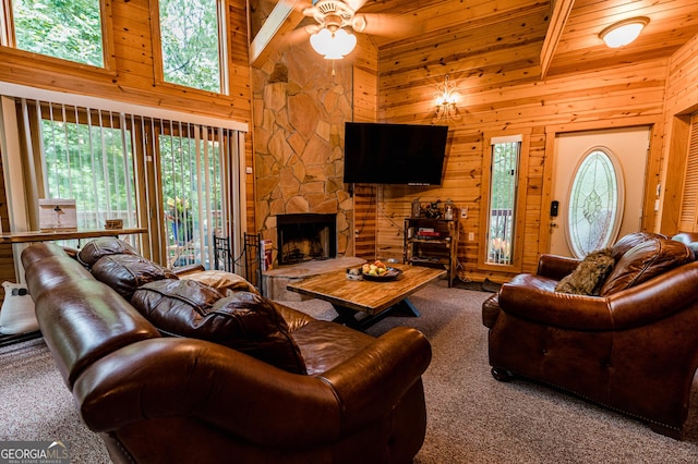 living room with a stone fireplace, high vaulted ceiling, beamed ceiling, carpet floors, and wooden ceiling