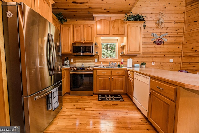 kitchen with sink, wood walls, wood ceiling, light hardwood / wood-style flooring, and stainless steel appliances