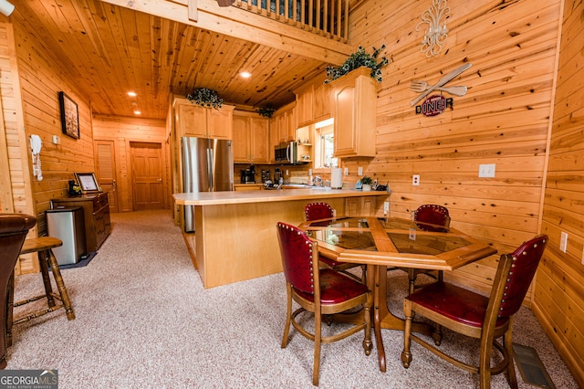 kitchen featuring appliances with stainless steel finishes, light brown cabinetry, light colored carpet, kitchen peninsula, and wooden ceiling