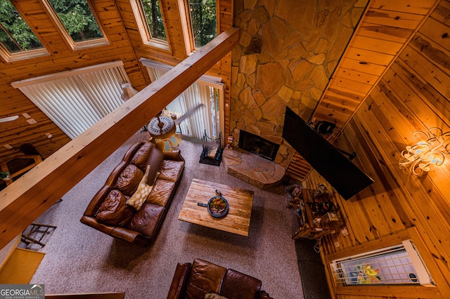 living room with wood walls, wood ceiling, a skylight, a towering ceiling, and a fireplace