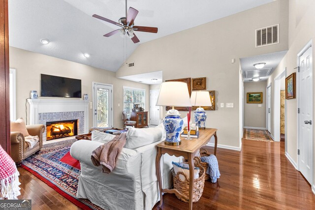 living room with hardwood / wood-style flooring, a tile fireplace, high vaulted ceiling, and ceiling fan