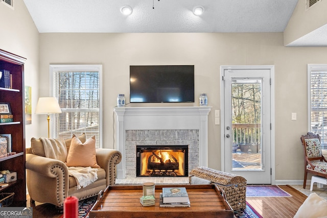 living room with lofted ceiling, a brick fireplace, and hardwood / wood-style flooring