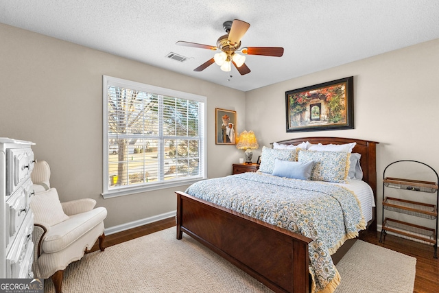 bedroom with a textured ceiling, wood-type flooring, and ceiling fan