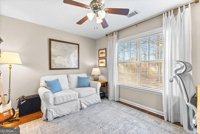 sitting room featuring wood-type flooring, ceiling fan, and a textured ceiling