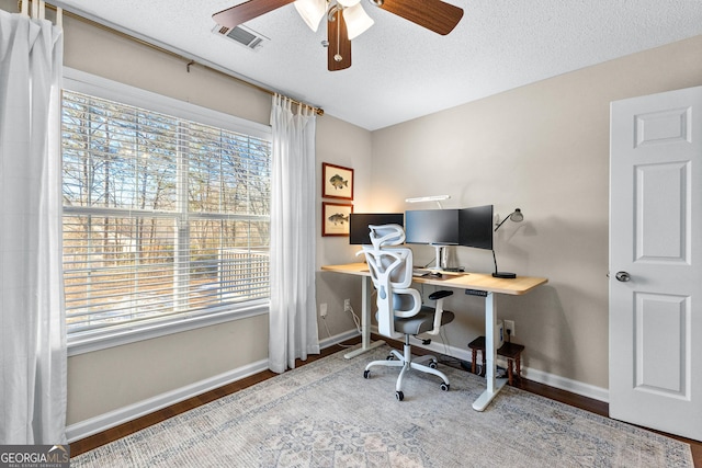 home office with wood-type flooring, plenty of natural light, ceiling fan, and a textured ceiling