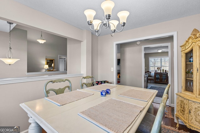 dining space featuring an inviting chandelier, dark hardwood / wood-style flooring, and a textured ceiling