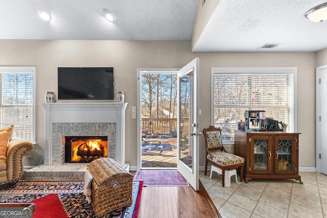 tiled living room featuring a fireplace, plenty of natural light, and a textured ceiling