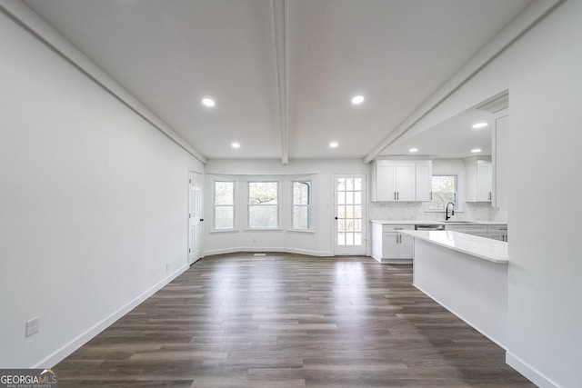 unfurnished living room featuring beamed ceiling, sink, and dark hardwood / wood-style flooring