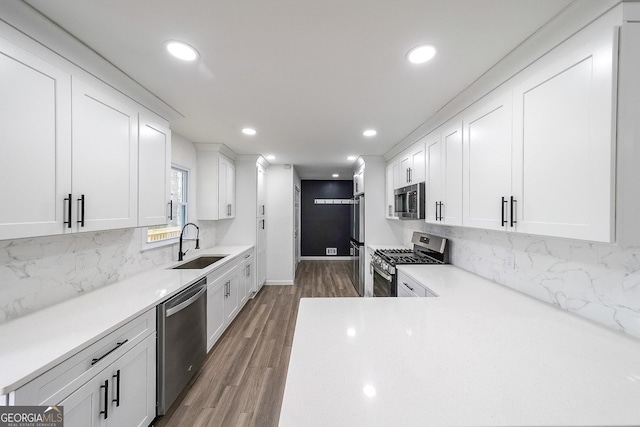 kitchen with appliances with stainless steel finishes, sink, decorative backsplash, and white cabinets