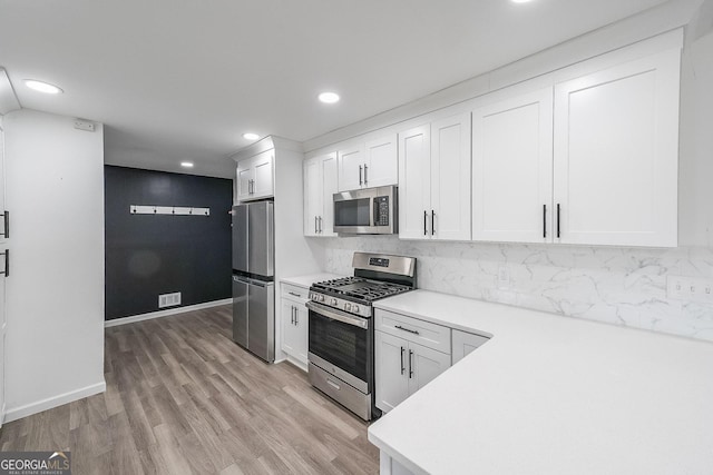 kitchen featuring backsplash, stainless steel appliances, light hardwood / wood-style flooring, and white cabinets