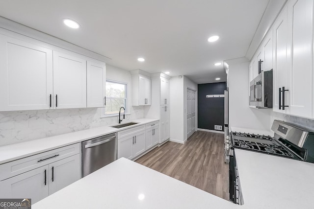 kitchen featuring hardwood / wood-style flooring, appliances with stainless steel finishes, sink, and white cabinets