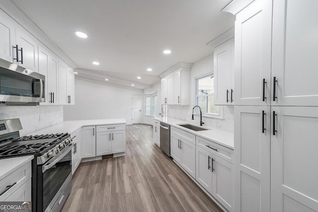 kitchen featuring stainless steel appliances, sink, white cabinets, and light hardwood / wood-style flooring