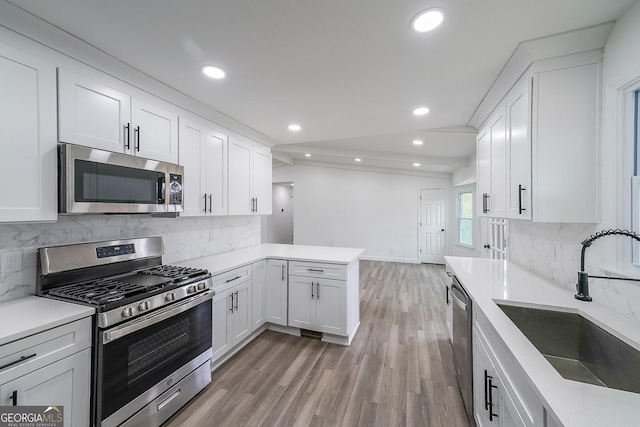 kitchen featuring appliances with stainless steel finishes, sink, white cabinets, and kitchen peninsula