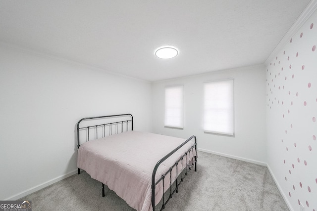 bedroom with ornamental molding and light colored carpet