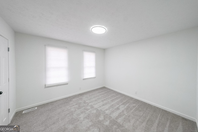 empty room with carpet and a textured ceiling