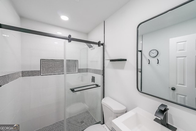 bathroom featuring sink, a shower with door, and toilet