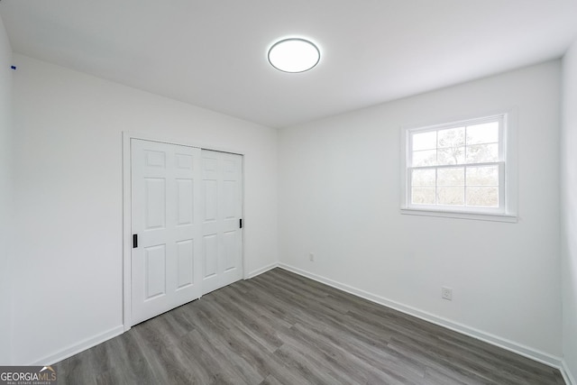 unfurnished bedroom featuring dark wood-type flooring and a closet