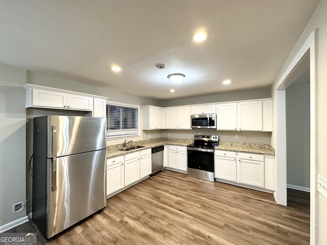 3880 Springleaf Ct, Stone Mountain, GA 30083 - kitchen featuring sink, white cabinetry, light stone counters, light wood-type flooring, and appliances with stainless steel finishes