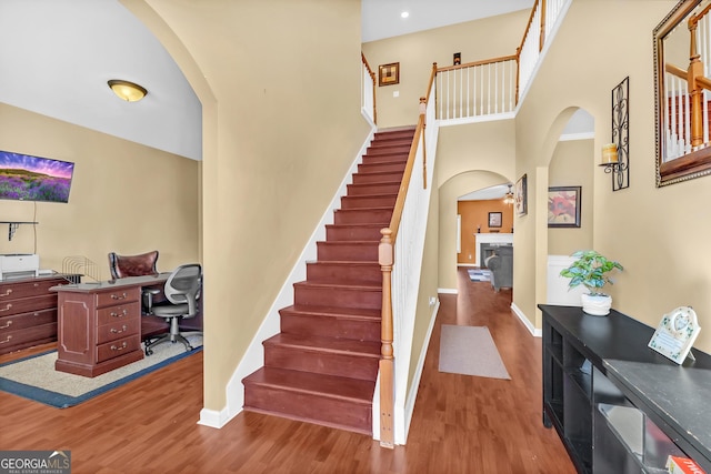 stairway with hardwood / wood-style flooring and a high ceiling